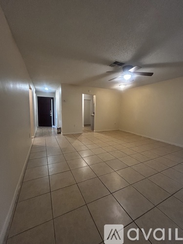 A spacious room with tiled flooring and a ceiling fan.