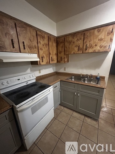 A kitchen with wooden cabinets and a white stove top oven.