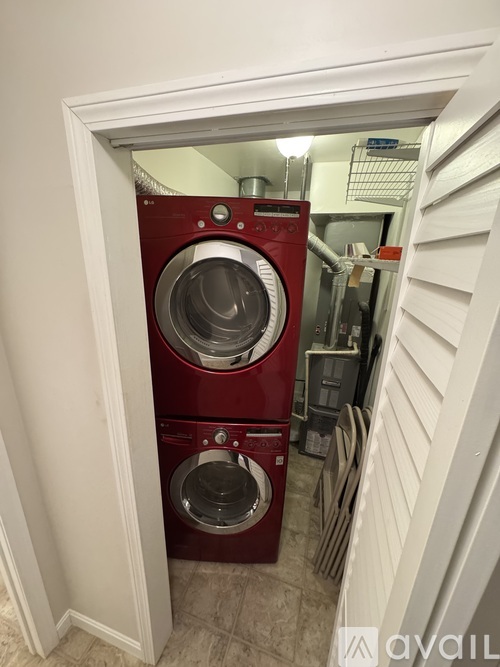 A red washing machine is in a small doorway.