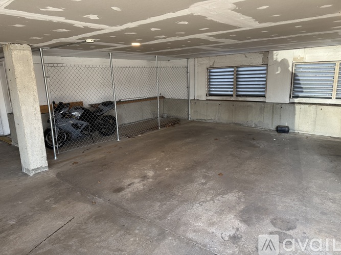 A large, empty room with a chain link fence and a concrete floor.
