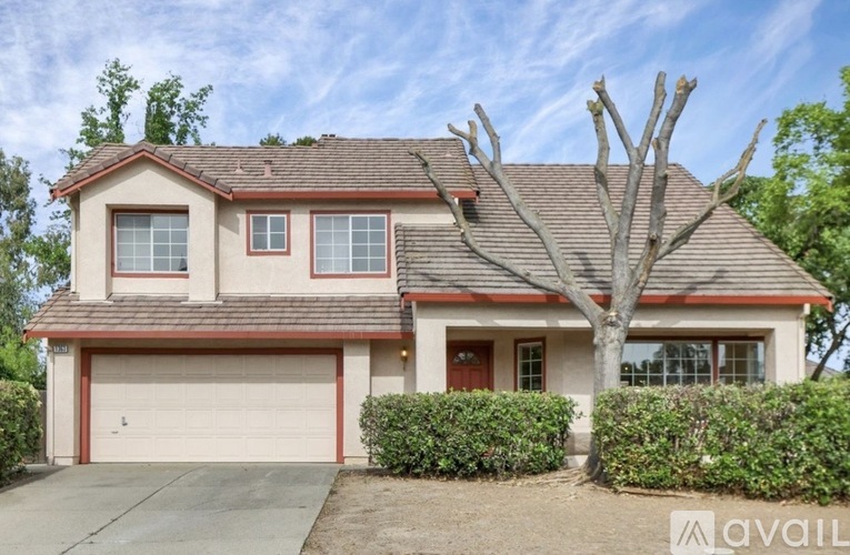 A house with a brown roof and a tree in front.
