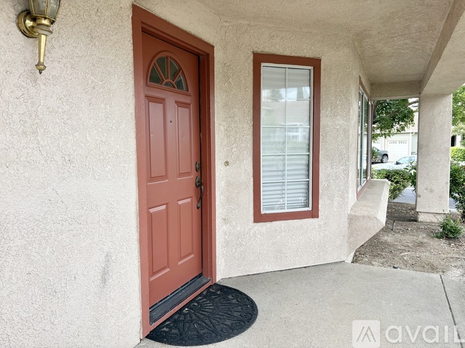 A red door is on the left side of a house with a window on the right.