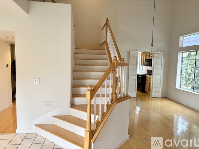 A wooden staircase with a white landing and a chandelier hangs from the ceiling.