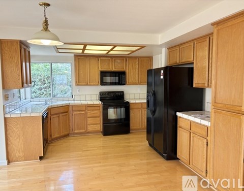 A kitchen with wooden cabinets and black appliances.