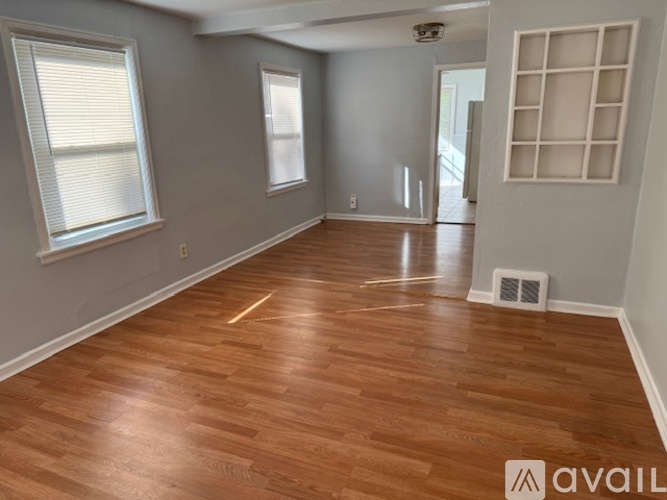 A room with wooden flooring and a window with blinds.