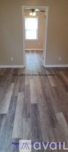 A room with wooden flooring and a doorway leading to another room.