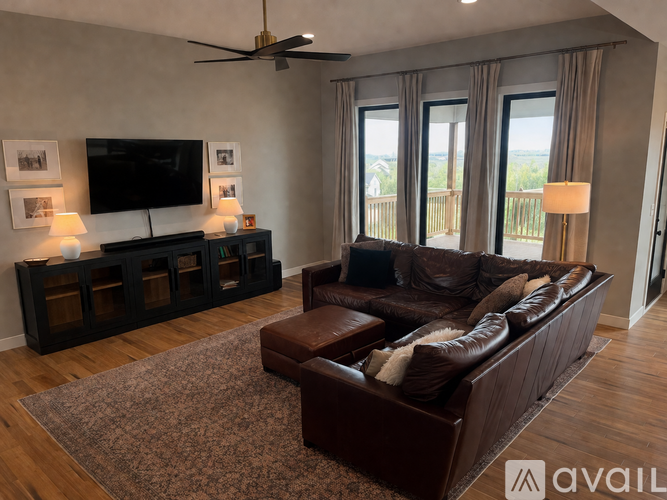 A living room with a brown leather couch and a television on a black stand.
