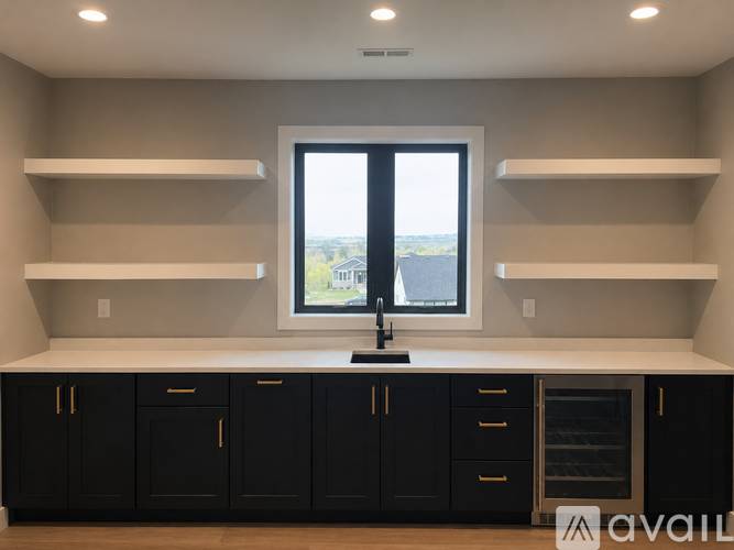 A kitchen with black cabinets and a window overlooking a landscape.