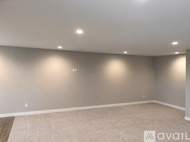 A spacious room with a carpeted floor and recessed lighting.