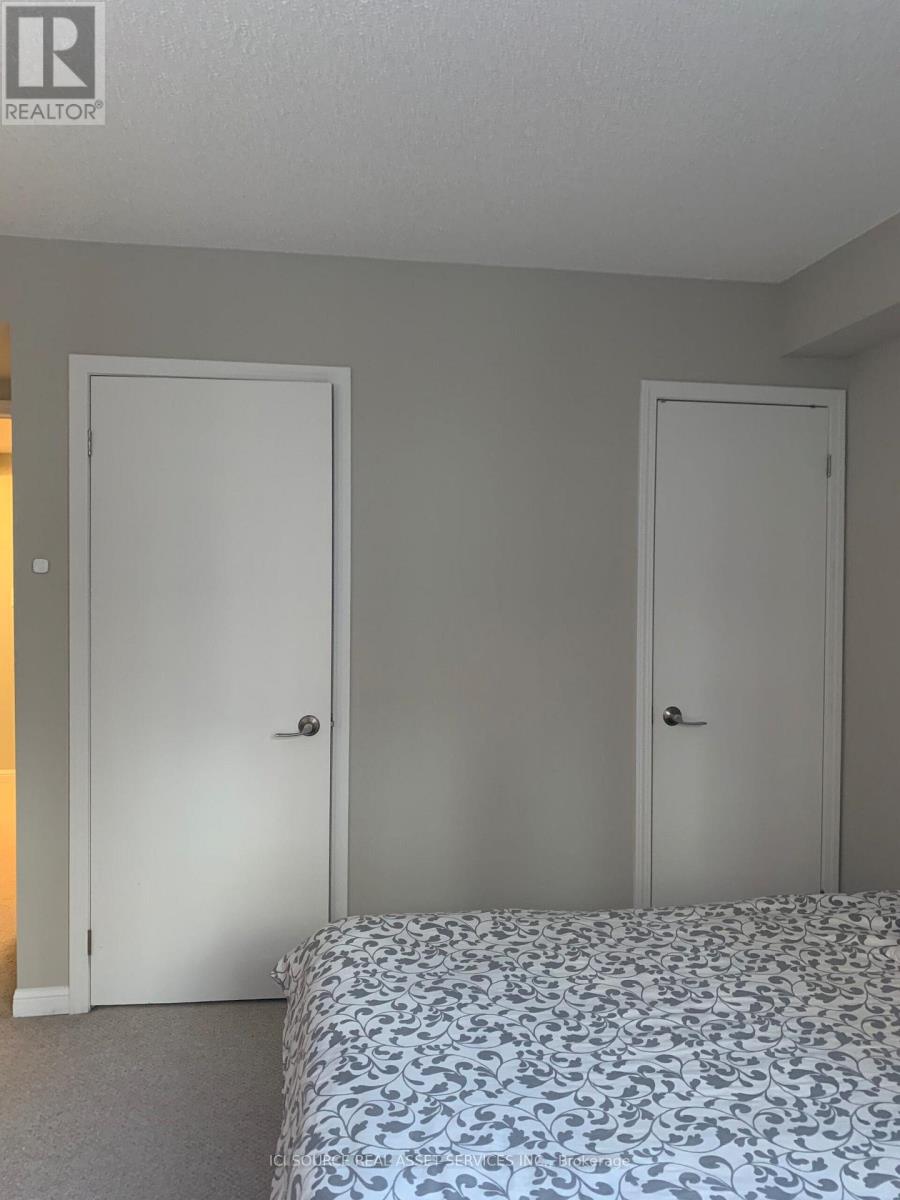 A bedroom with two doors and a bed with a patterned cover.