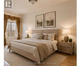 A bedroom with a large bed, two nightstands, and pictures on the wall.