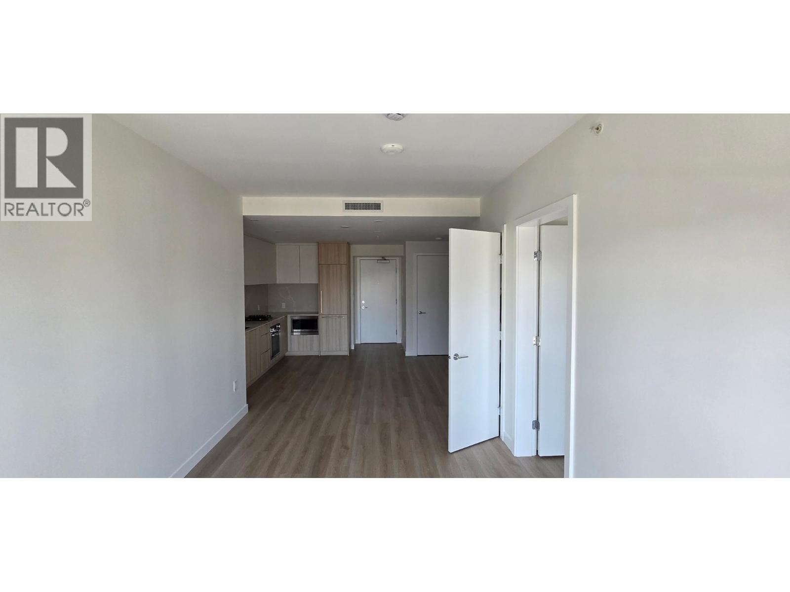 A realtor logo is on the wall of a room with a kitchen in the background.