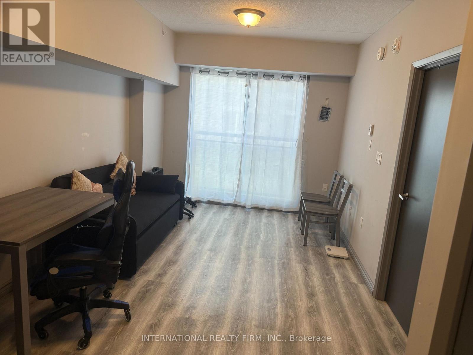 A room with a desk and a couch with a window behind it.