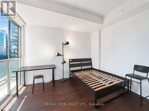 A bedroom with a bed, chair, and desk.