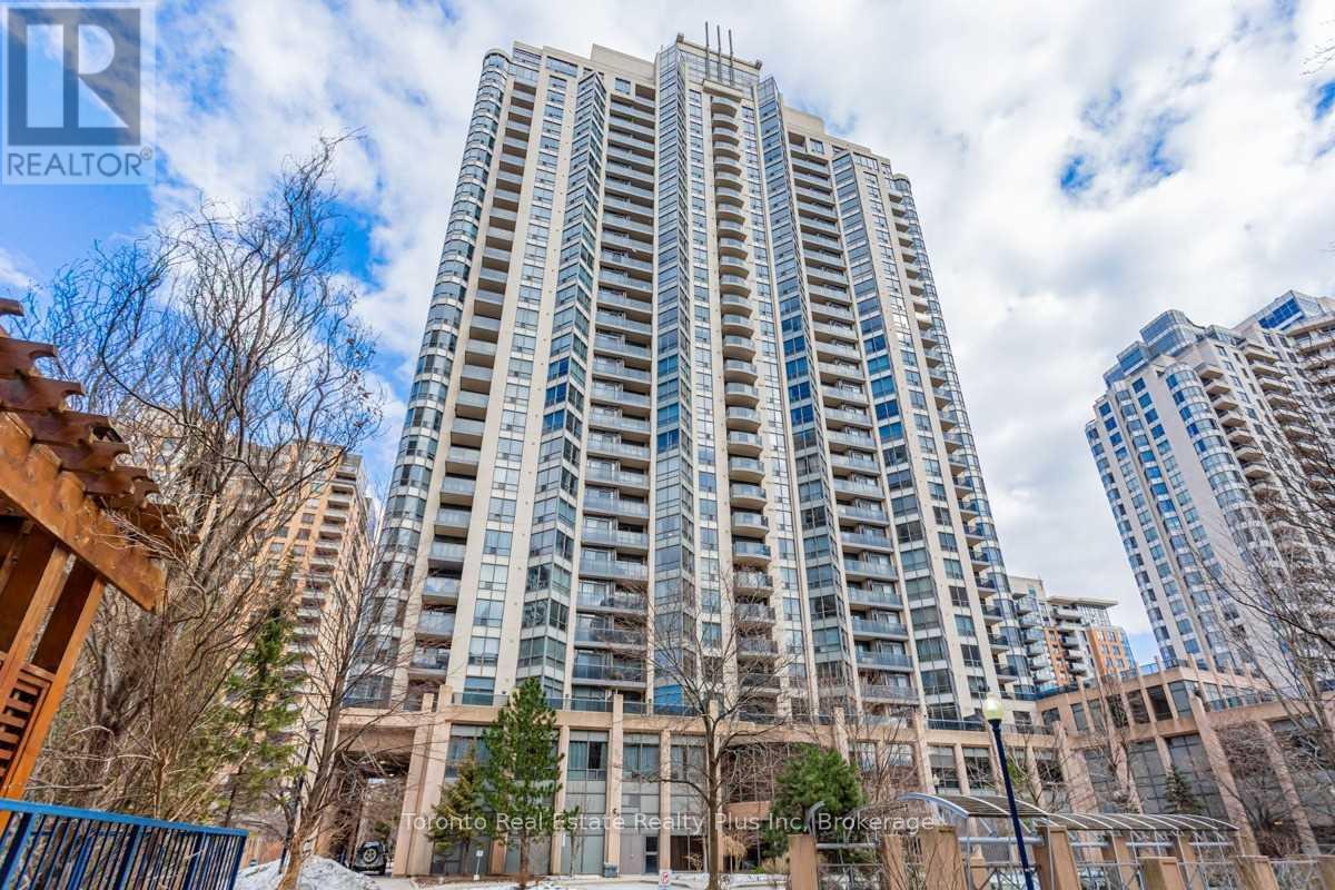 A tall residential building with many windows and balconies is surrounded by other buildings.