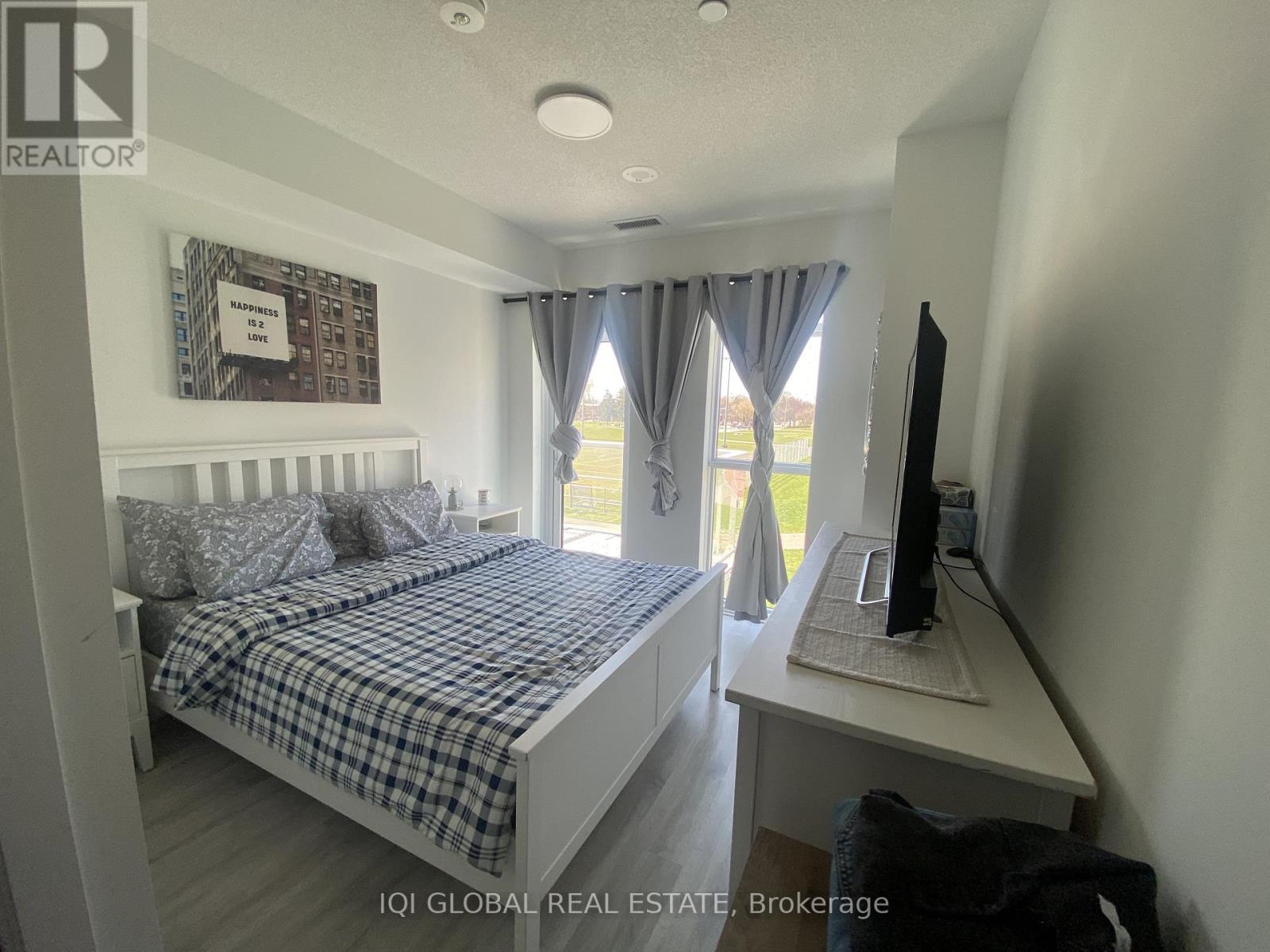 A bedroom with a bed, desk, and window.