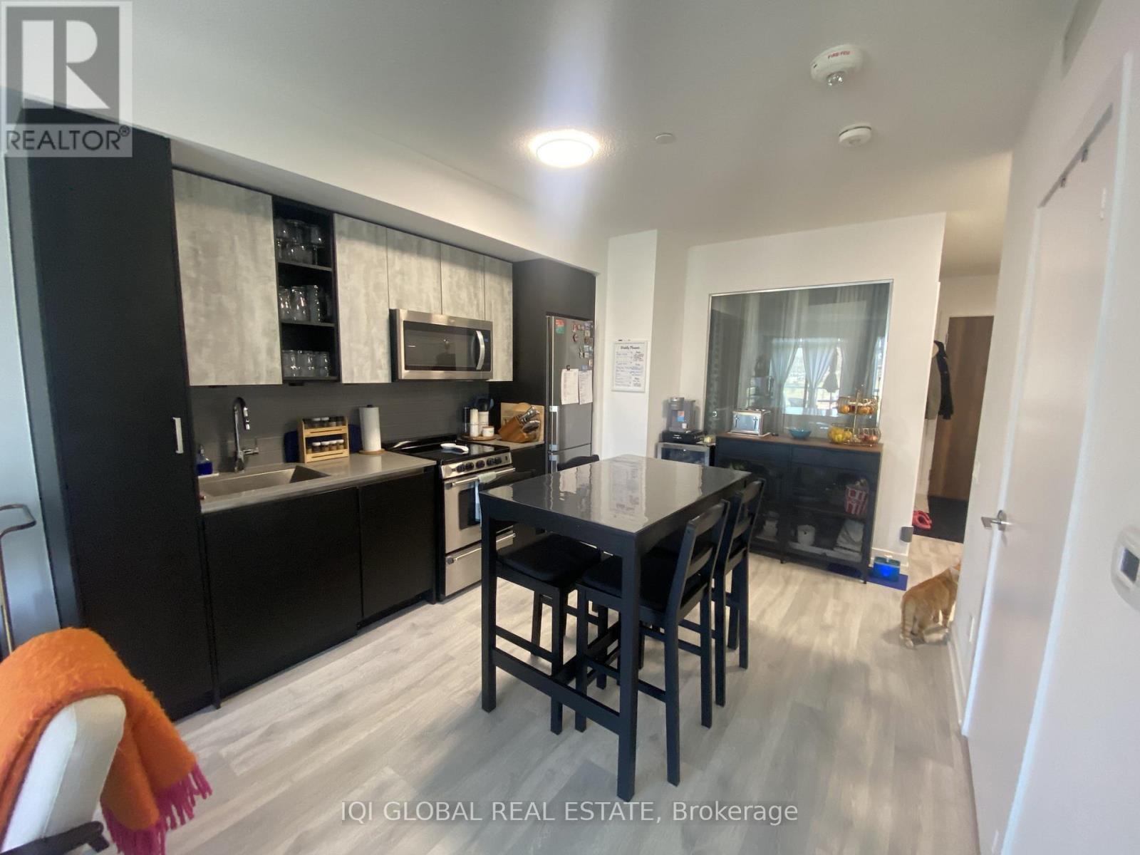 A modern kitchen with black cabinets and a dining table.