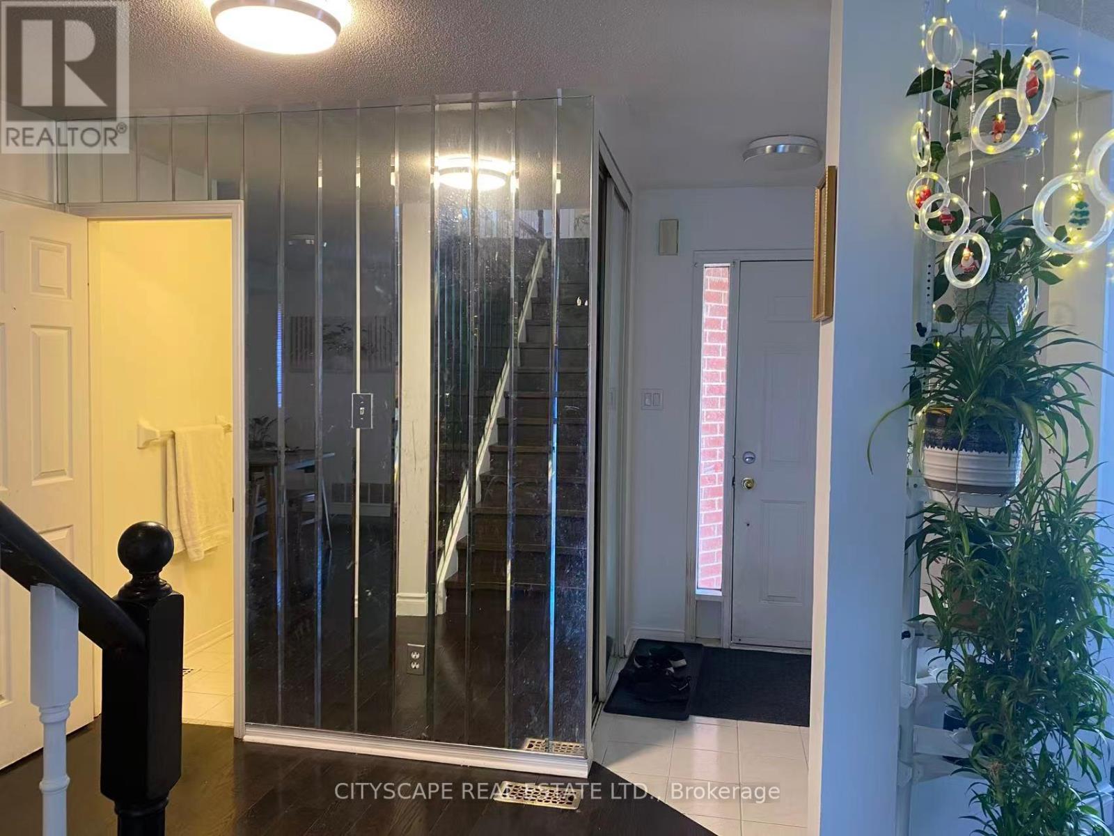 A hallway with a glass door and a plant on the right side.