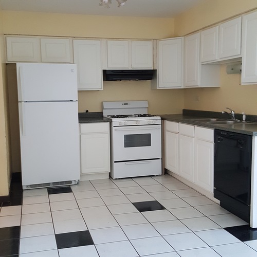 A kitchen with white appliances and black and white tiles.