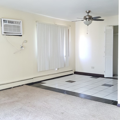 A room with a ceiling fan and a window with blinds.