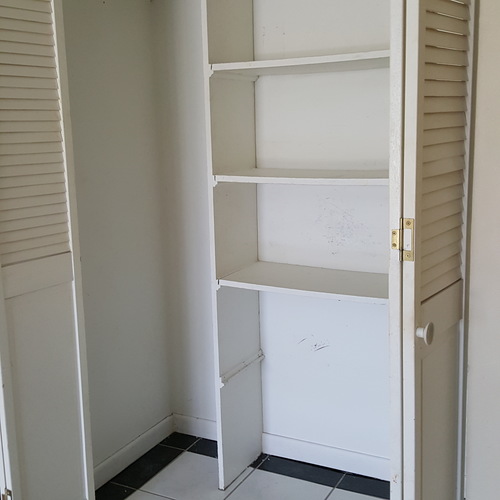 A white closet with shelves and a door.