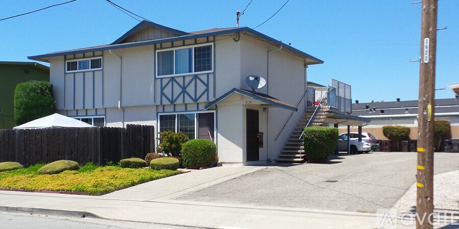 A house with a grey and white facade has a brown telephone pole in front of it.