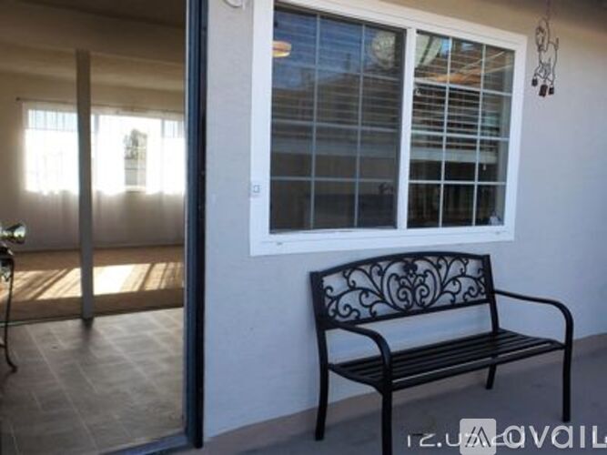 A black bench with a decorative design sits in front of a window.