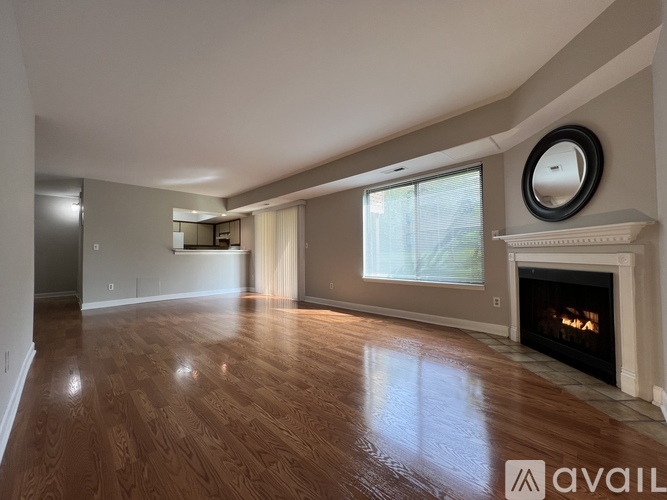 A spacious living room with wood flooring and a fireplace.