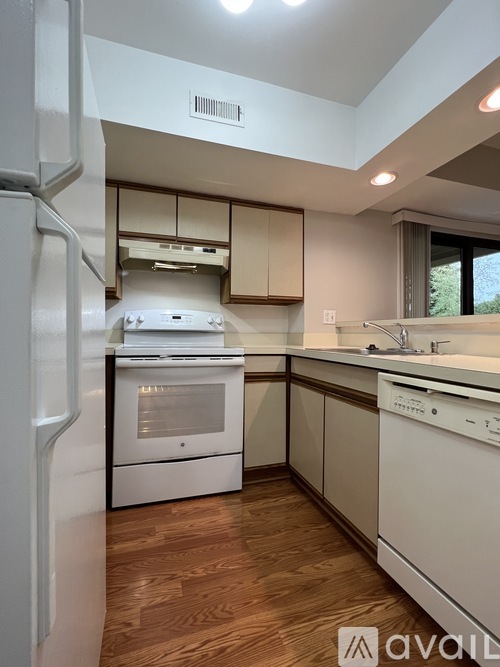 A kitchen with white appliances and wooden floors.
