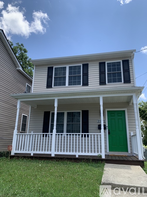 A two-story house with a green door and white porch.
