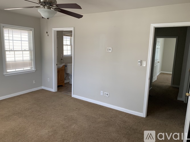 A room with a ceiling fan and carpeted floor.