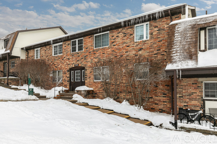 A red brick house with snow on the ground and a black door.
