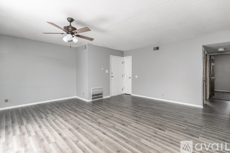 A spacious room with a ceiling fan and wooden flooring.