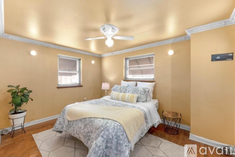 A bedroom with a bed, a plant, and a ceiling fan.