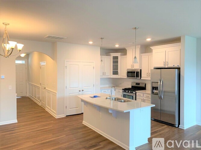 A kitchen with white cabinets and a white island with a sink.