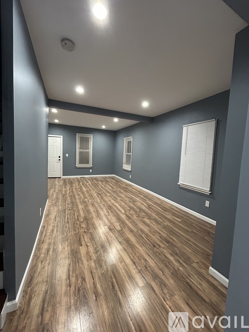 A spacious room with wooden flooring and white walls.