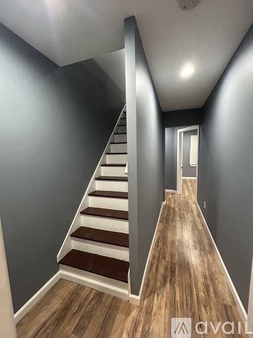 A wooden staircase with a white railing and steps leading to a door.