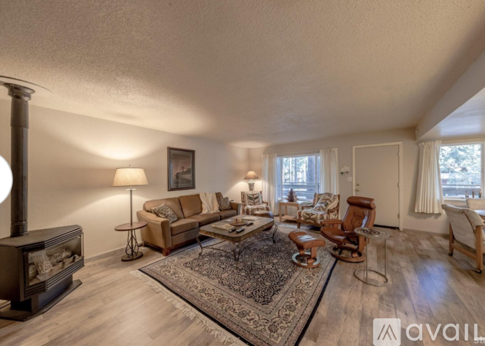 A living room with a wood stove and a rug on the floor.
