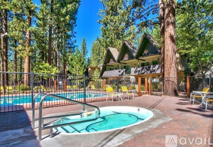 A pool surrounded by trees and a house in the background.