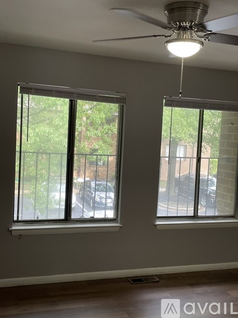 A room with two windows and a ceiling fan.