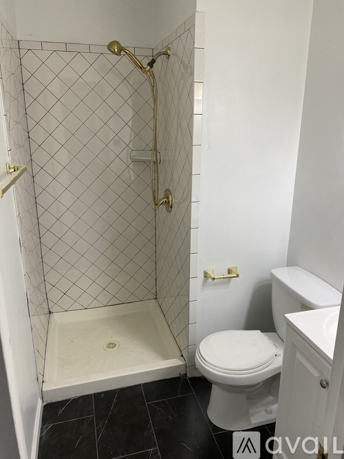 A white toilet in a bathroom with a black floor and a white shower stall.