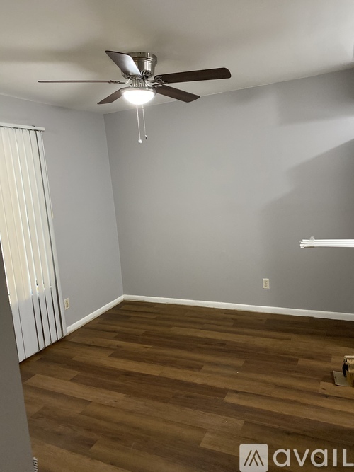 A room with a ceiling fan and wooden flooring.
