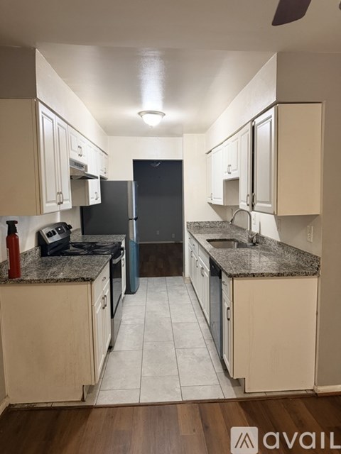 A kitchen with white cabinets and a black refrigerator.