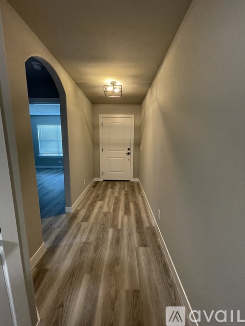 A hallway with a wooden floor and a white door.