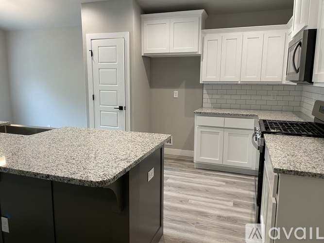A kitchen with white cabinets and a granite countertop.