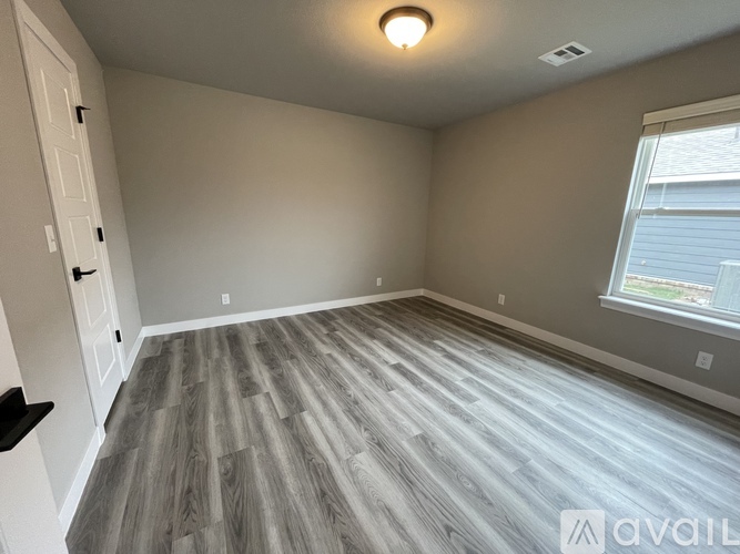 A room with wooden flooring and a window with blinds.