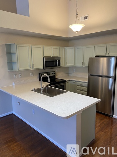 A kitchen with a white counter top and a stainless steel refrigerator.
