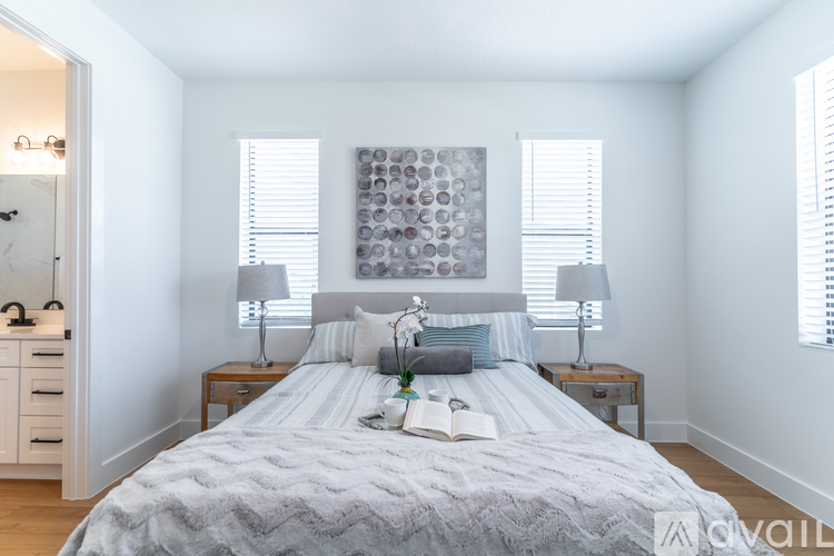 A bedroom with a bed, two lamps, and a painting on the wall.