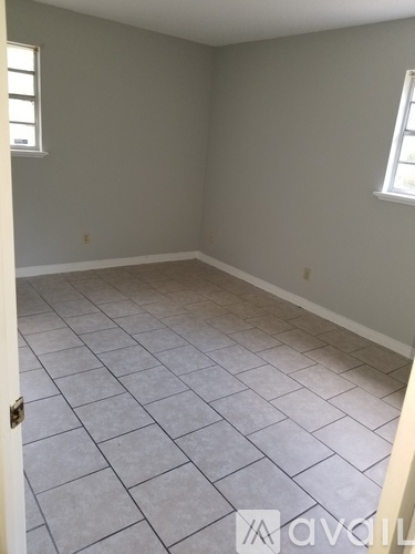 A room with tile flooring and two windows.