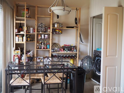 A kitchen with a table and chairs and a shelf with many bottles and containers.
